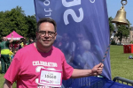 Craig Hoy MSP ringing bell at finish of Race for Life at Holyrood Park